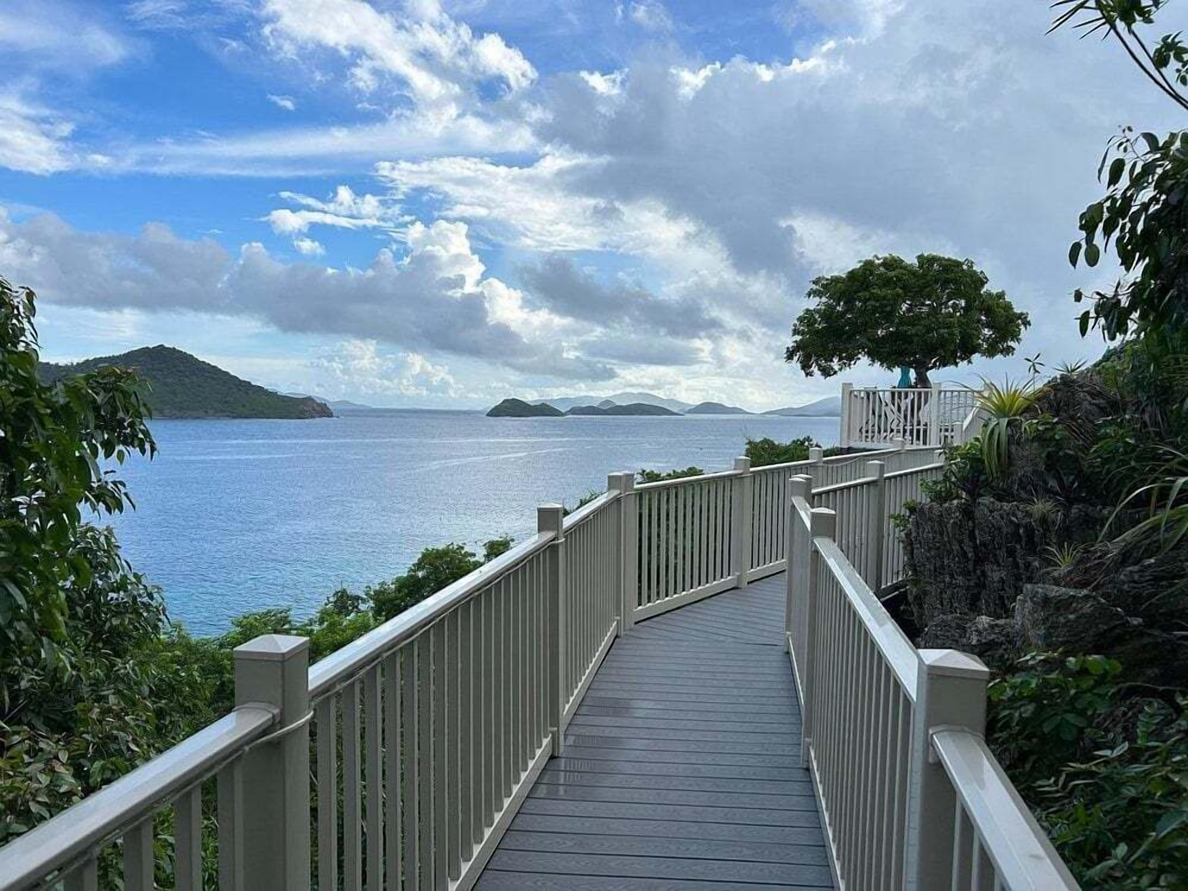 A wooden pathway leading to a viewpoint overlooking a body of water with distant landforms.