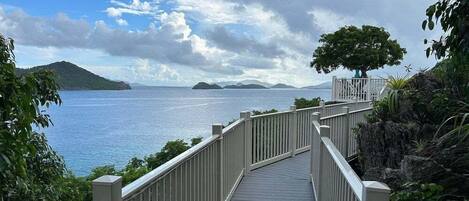 A wooden pathway leading to a viewpoint overlooking a body of water with distant landforms.