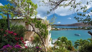 A coastal building with a balcony overlooking turquoise waters and boats. - Point Pleasant Resort (St. Thomas)