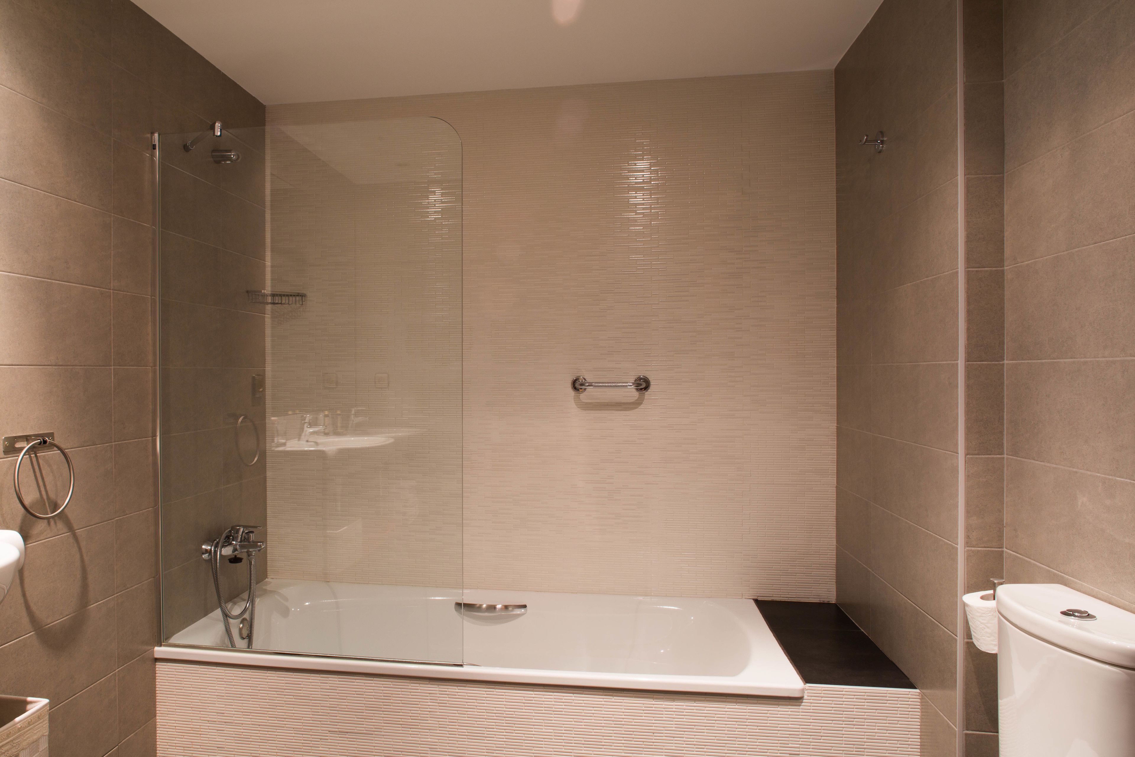 Un baño moderno con ducha de vidrio, una bañera independiente y un inodoro.