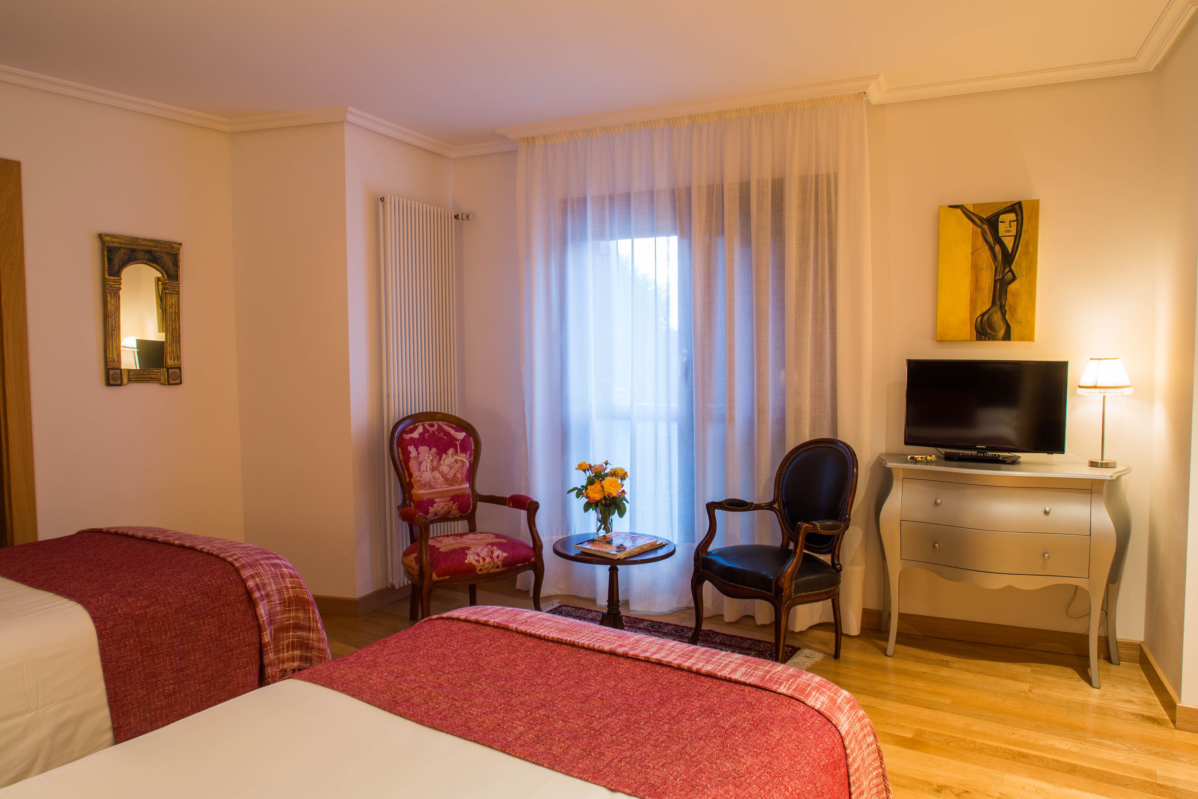 A hotel room with two beds, a television, a desk, and a chair.