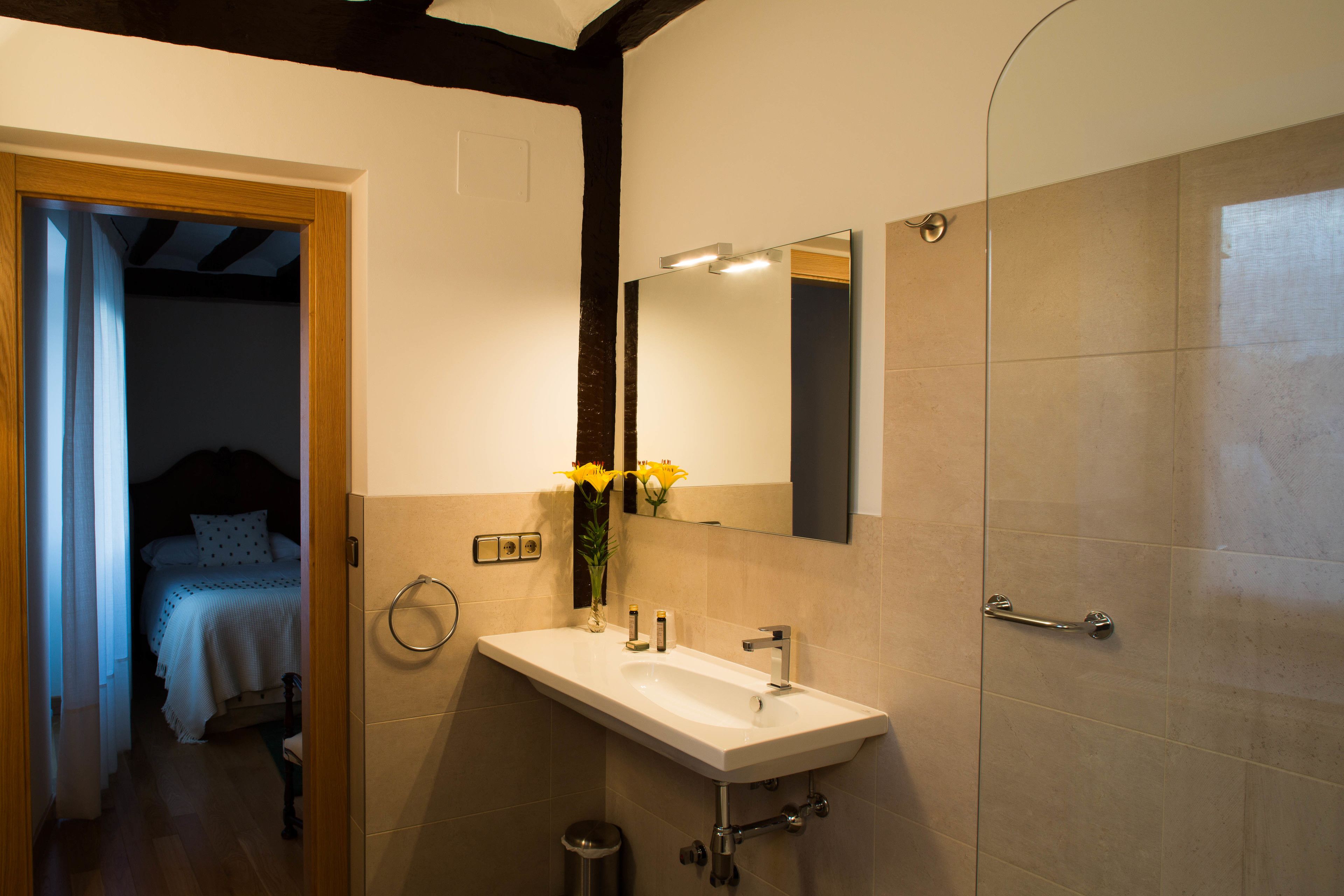 A bathroom with a sink, mirror, and shower.