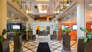 A hotel reception area with a check-in counter, seating, and potted plants. - Morning Side Suites (Lagos)