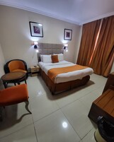 Una habitación de hotel con una cama, una silla, una mesita y una mesita de noche.