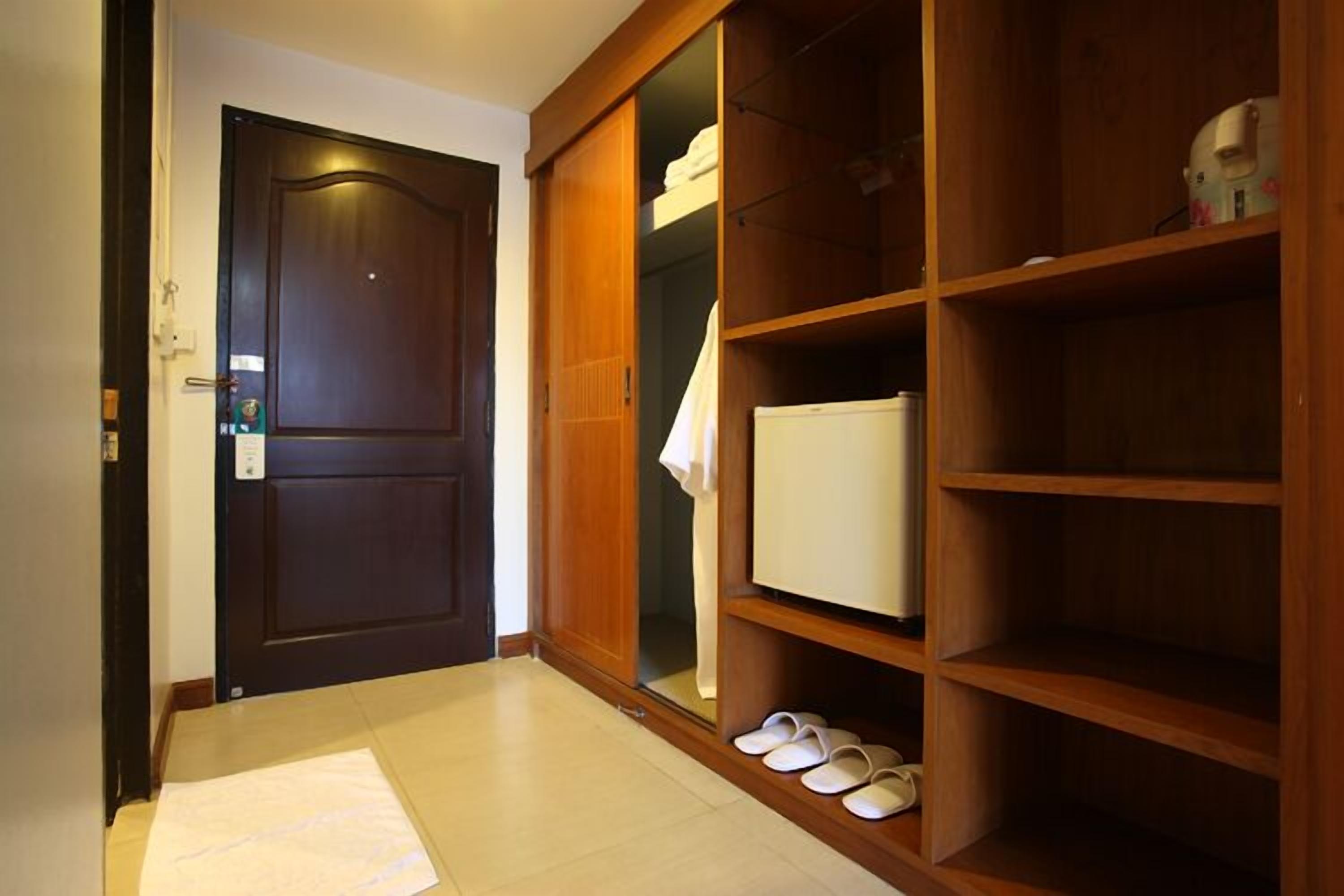 Een houten garderobe met verschillende planken, een deur en een paar slippers op de vloer.