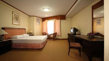 A hotel room with a bed, desk, chair, and a television.