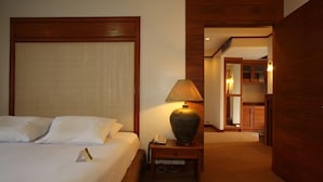 A hotel room with a large bed, a bedside lamp, and a wooden nightstand. - Royal Diamond Hotel (Phetchaburi)