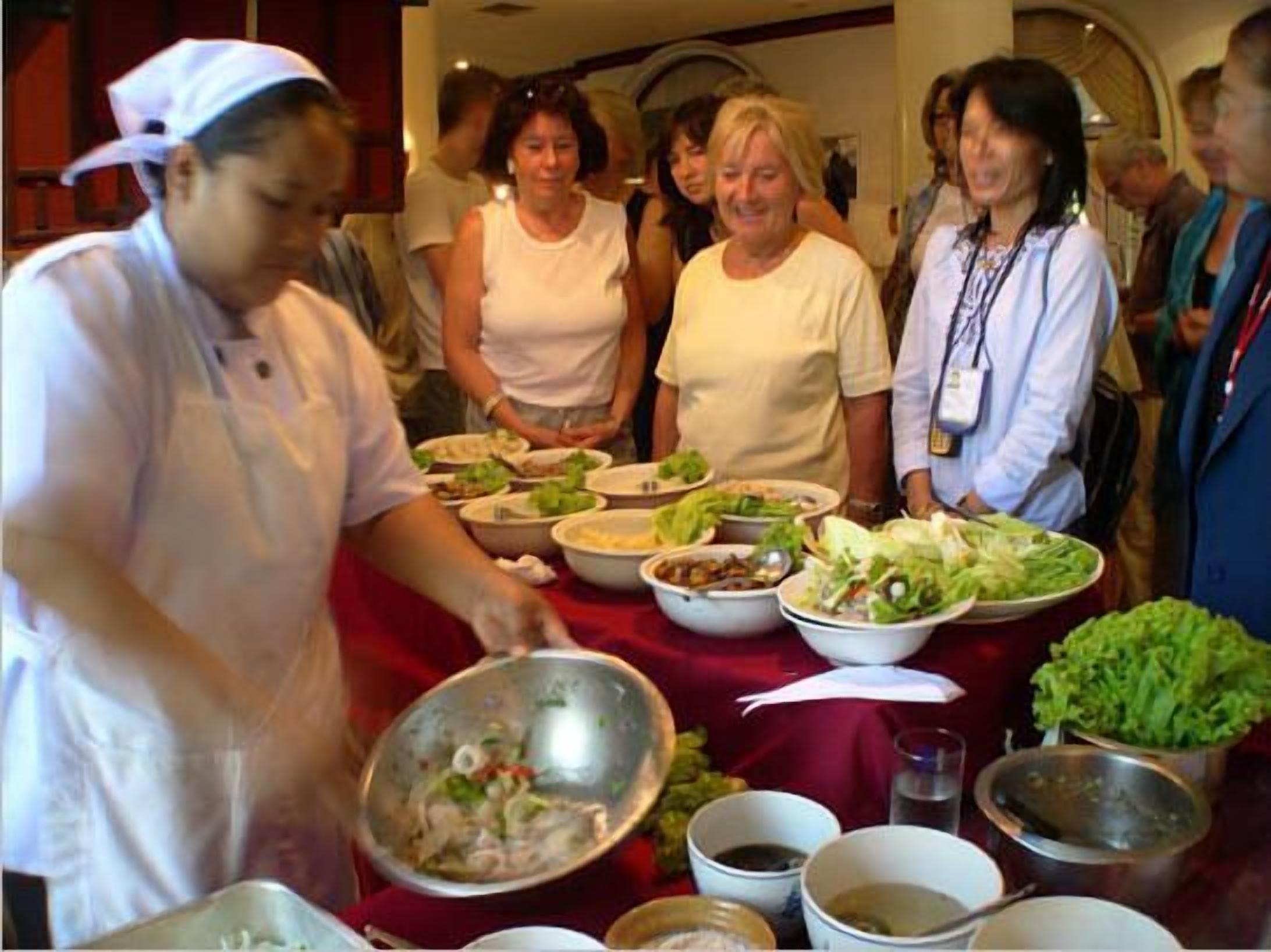 A buffet setup with various dishes and a person serving food.