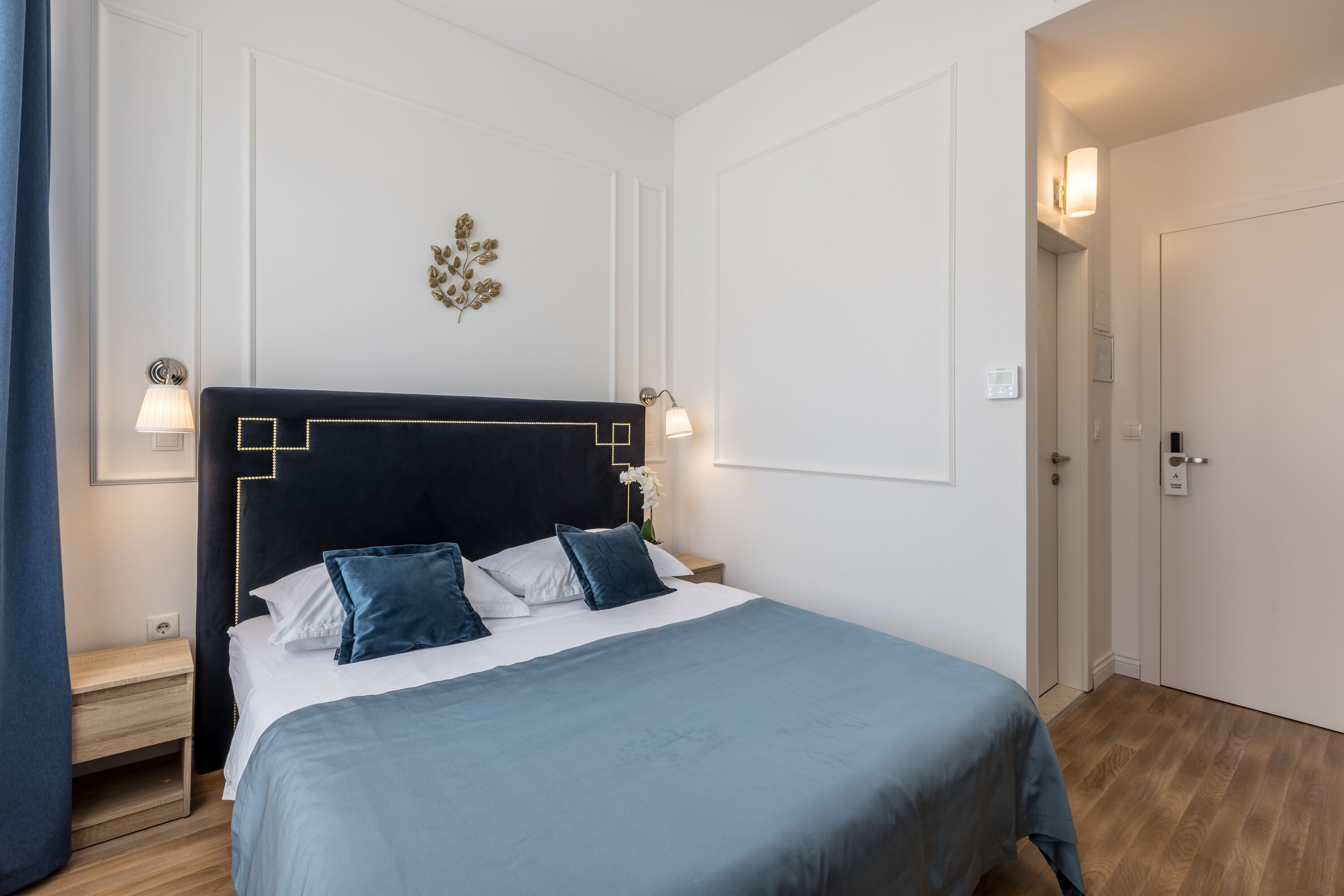 A neatly arranged bedroom with a bed, bedside tables, and a door.