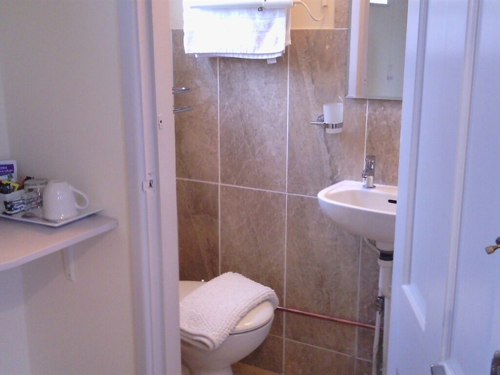 Un baño con inodoro, lavabo y una toalla colgada en la pared.