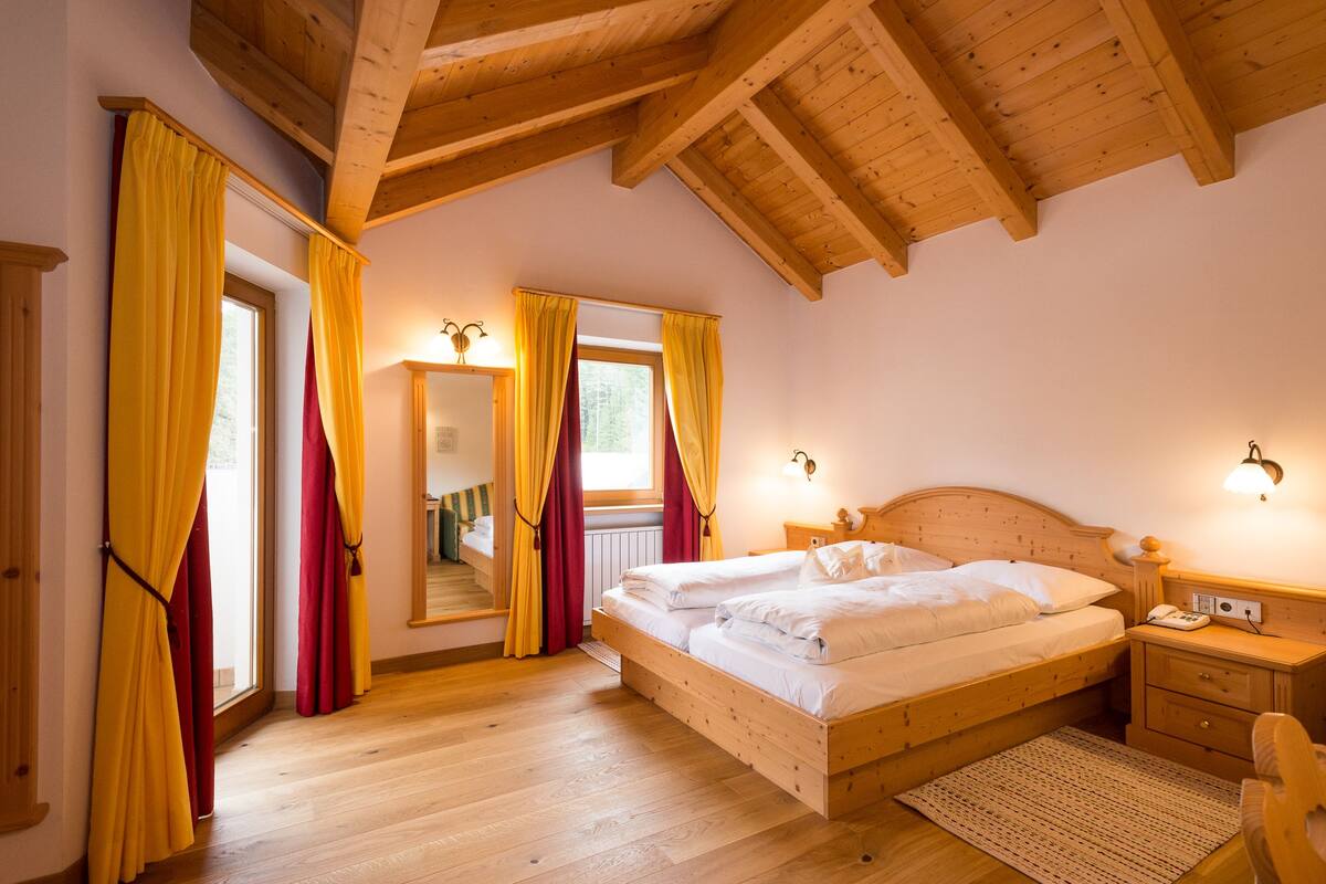Un dormitorio con estructura de madera, una cama, una mesita de noche y un espejo.