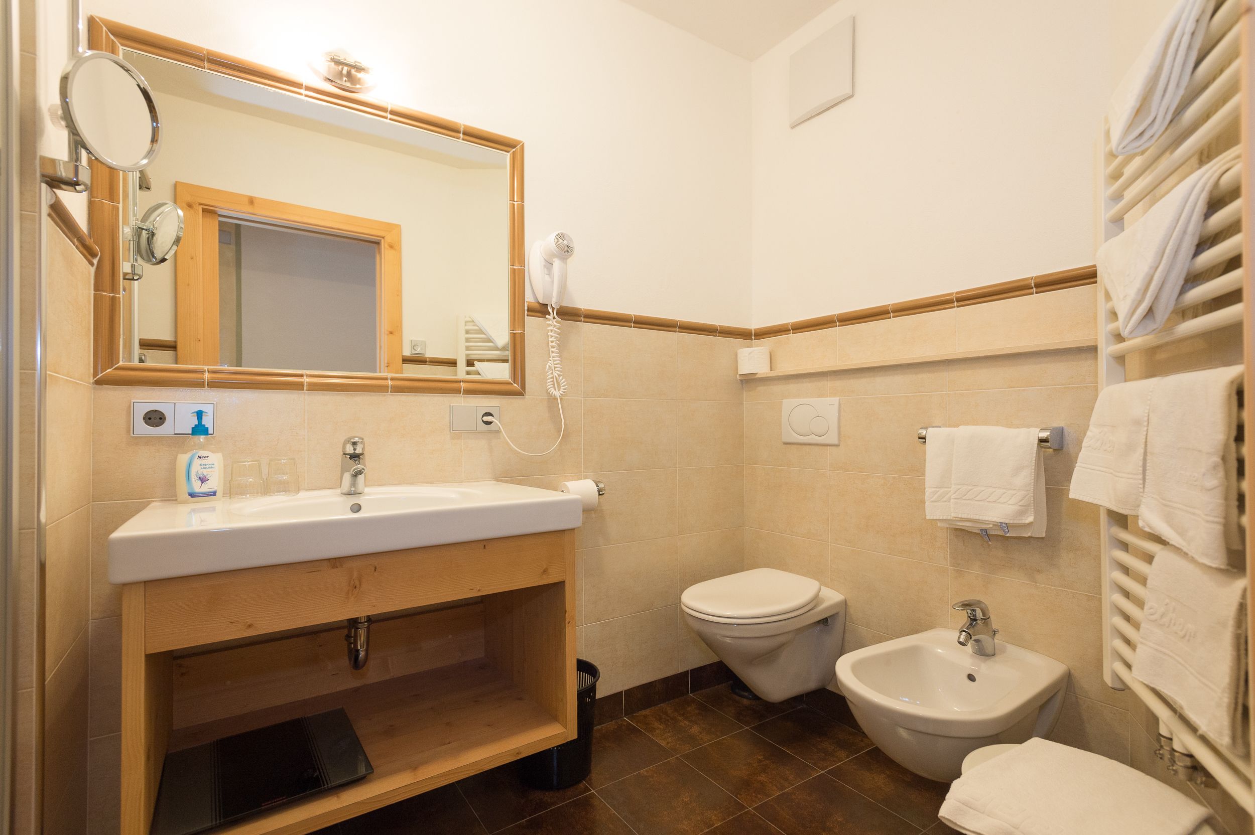 A bathroom with a sink, mirror, toilet, bidet, and towels.