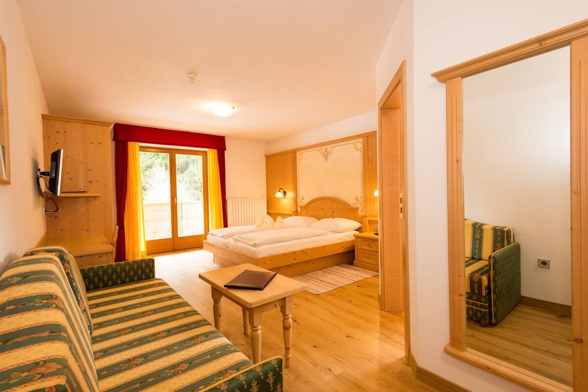 Un dormitorio acogedor con cama, una mesita, un sofá y un espejo.