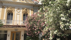 A hotel with ornate architecture, a balcony, and a garden with flowering trees. - Hôtel Belle Meunière (Nice)