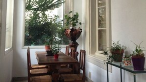 A dining area with a wooden table and chairs, surrounded by potted plants. - Hôtel Belle Meunière (Nice)