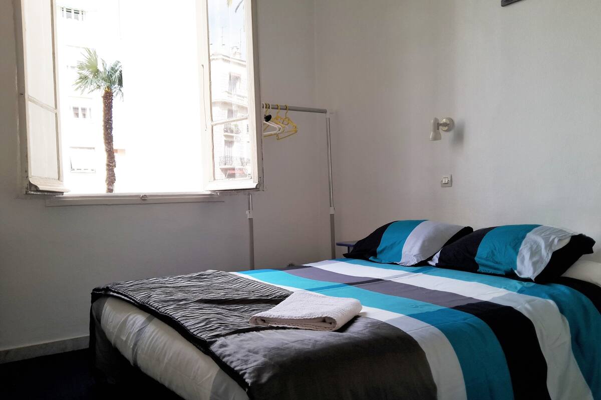 Un dormitorio con cama, ventana y lámpara colgante.