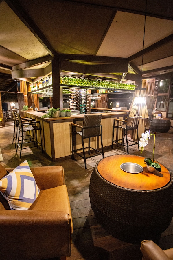 Eine Bar mit einer Holztresen, Barhocker und einer Hängelampe.