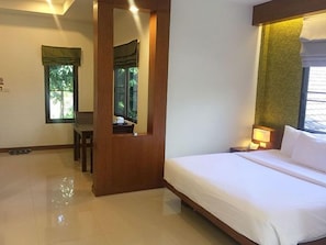 A hotel room with a bed, a chair, a desk, a mirror, and a window with curtains. - P.S Hill Resort (Patong)