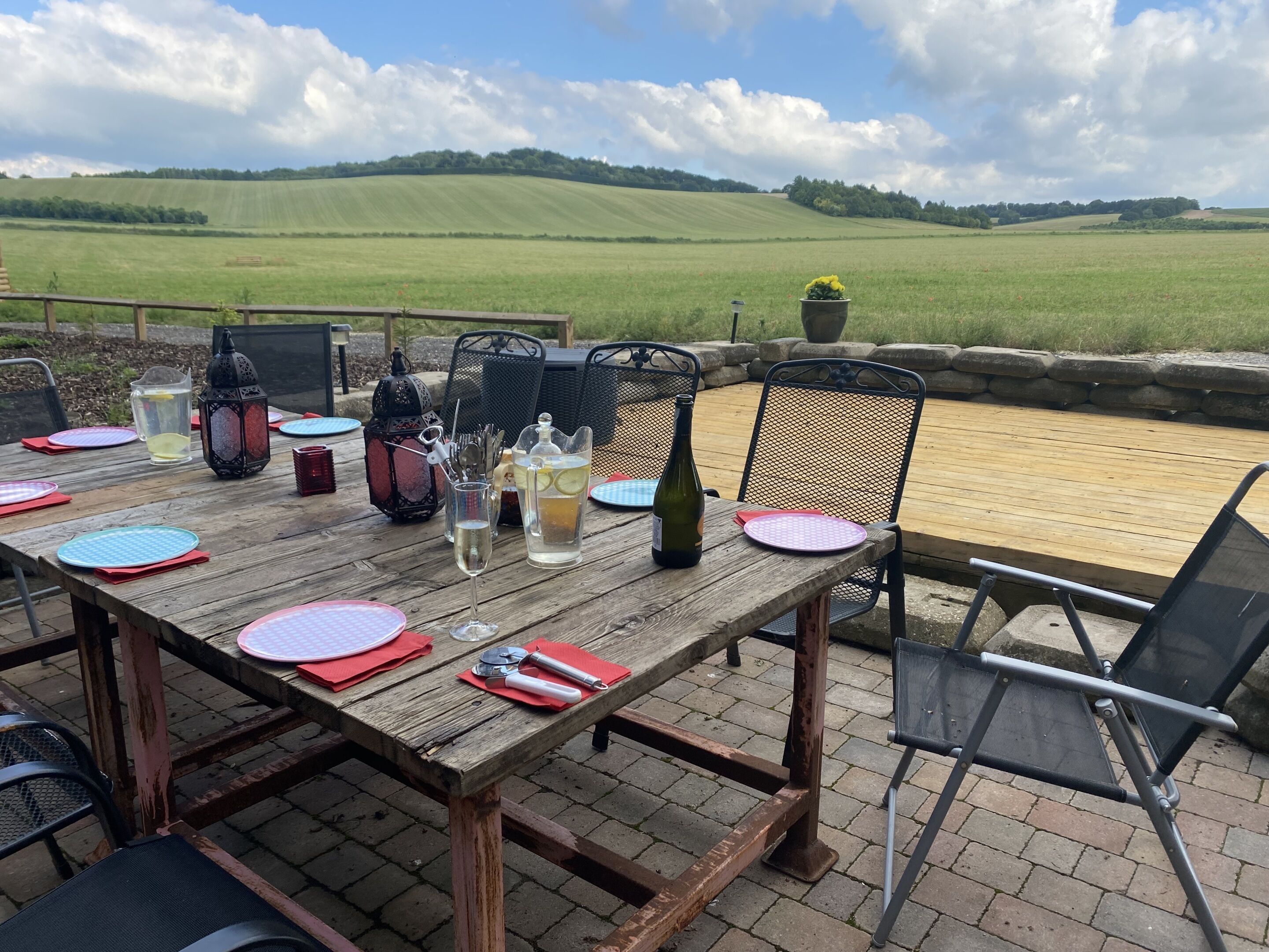 An outdoor dining area with a table set for four, featuring a view of rolling hills.