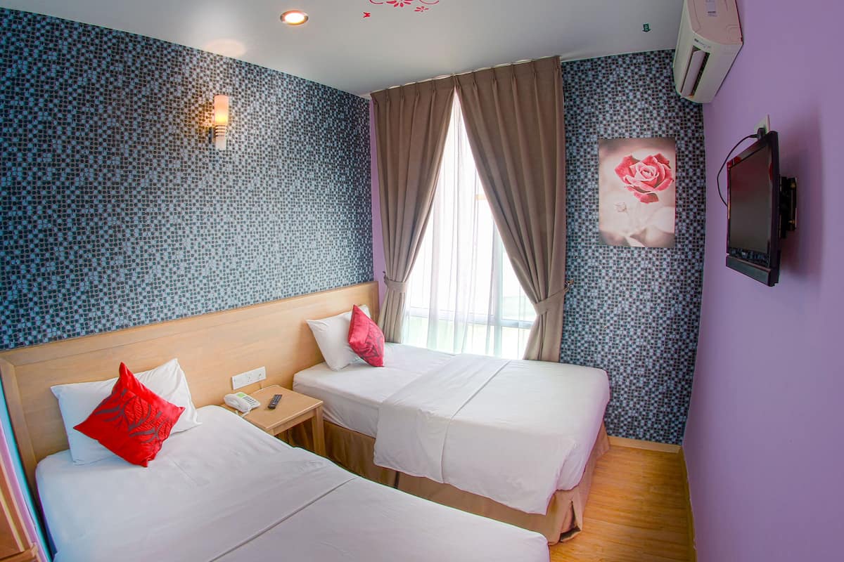 A hotel room with two beds, a nightstand, a telephone, and a wall-mounted TV.