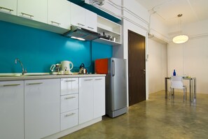 A modern kitchen with white cabinets, a stainless steel refrigerator, and a teal backsplash. - T Series Place Serviced Apartment (Bangkok)