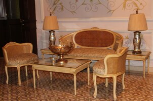 A room with a sofa, two armchairs, a coffee table, and two lamps.