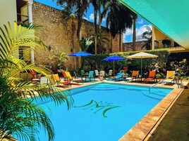 Una piscina al aire libre, sombrillas, sillones reclinables de piscina