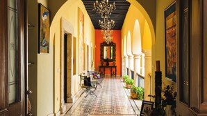 A hallway with a patterned floor, a chandelier, and framed artwork on the walls. - Mansión Merida Hotel Boutique - Restaurant  (Mérida)