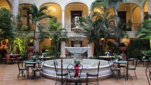 A courtyard with a central fountain, surrounded by outdoor seating and palm trees. - Mansión Merida Hotel Boutique - Restaurant  (Mérida)