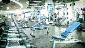 Et fitnesscenter med forskellig træningsudstyr, herunder håndvægte, træningsbænke og vægtmaskiner.