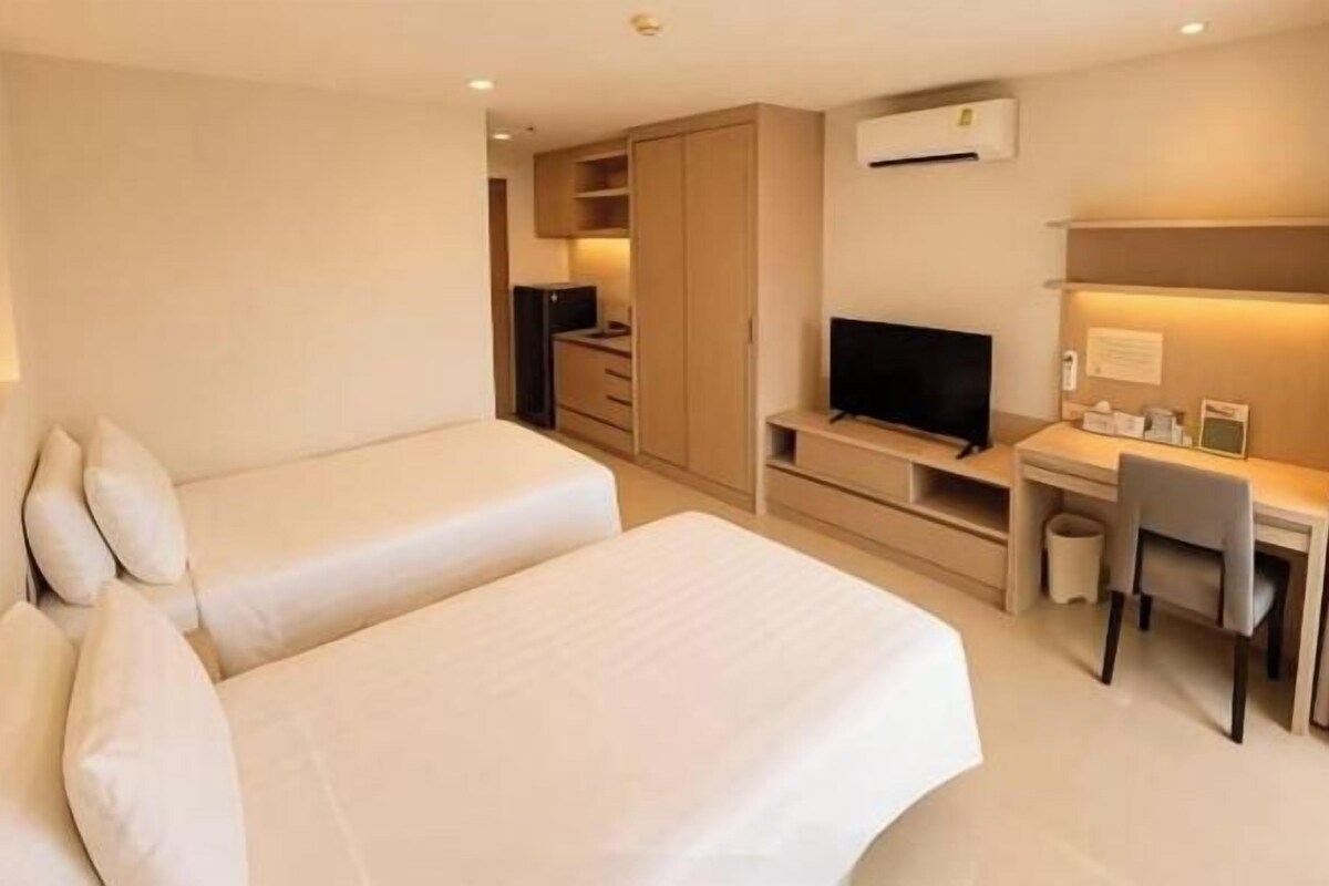 A hotel room with a bed, a desk, a chair, a television, and a wardrobe.