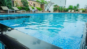 En swimmingpool med liggestole og plantekrukker.