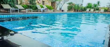 Una piscina al aire libre, sillones reclinables de piscina