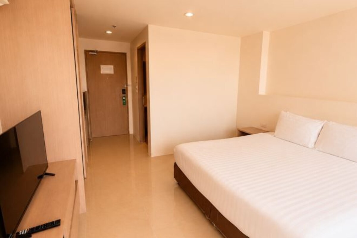 A hotel room with a bed, a television, and a door leading to another room.