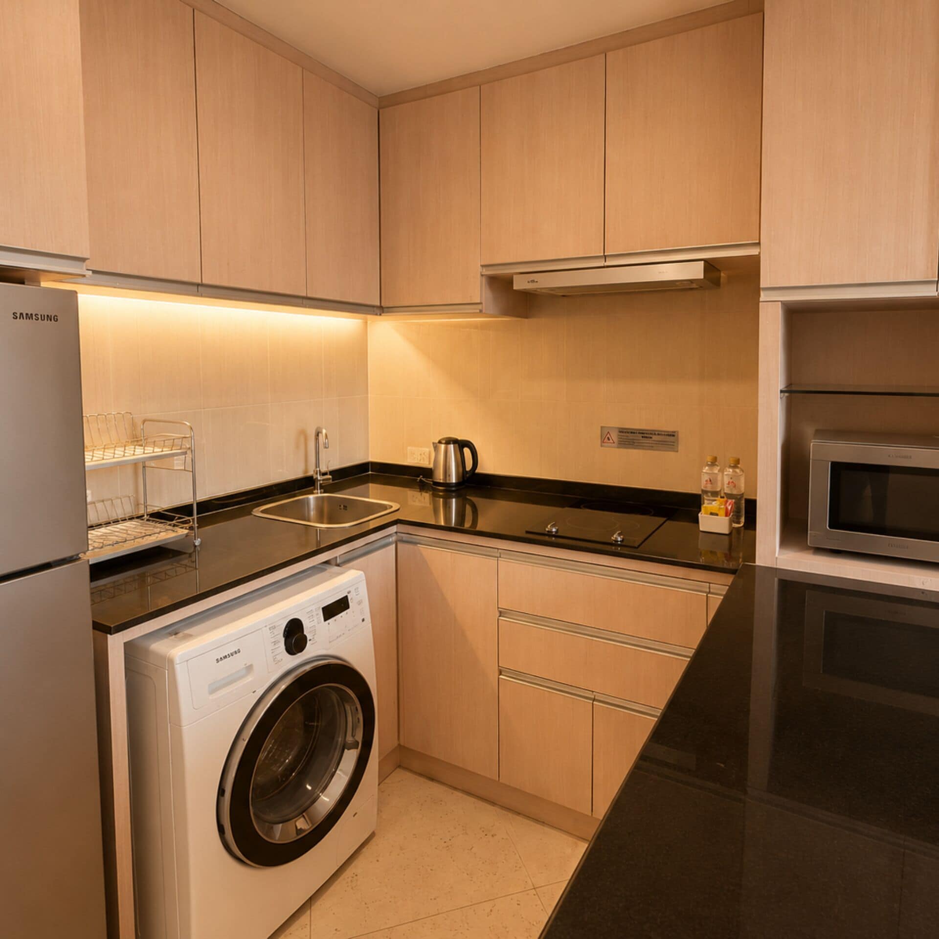 Una cocina moderna con lavadora integrada, electrodomésticos de acero inoxidable y armarios de madera.