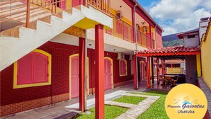 Un bâtiment à deux étages avec des murs en briques rouges, des éléments décoratifs jaunes et un toit recouvert de tuiles rouges.
