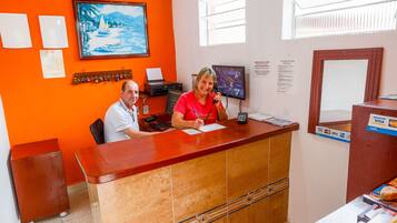 A reception desk with a wooden counter, a computer monitor, and a framed painting on the wall.