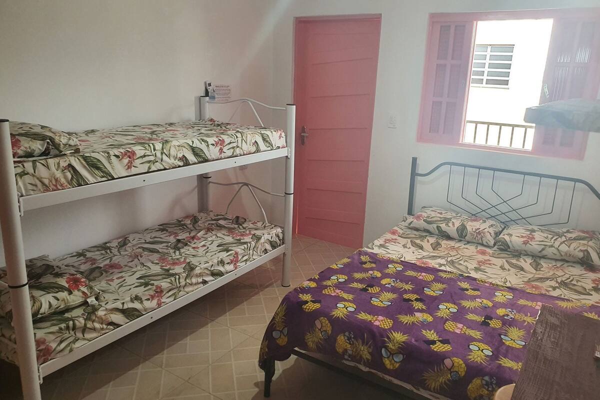 Une chambre de dortoir avec des lits superposés, un lit simple, une fenêtre donnant sur un paysage agréable et une porte.