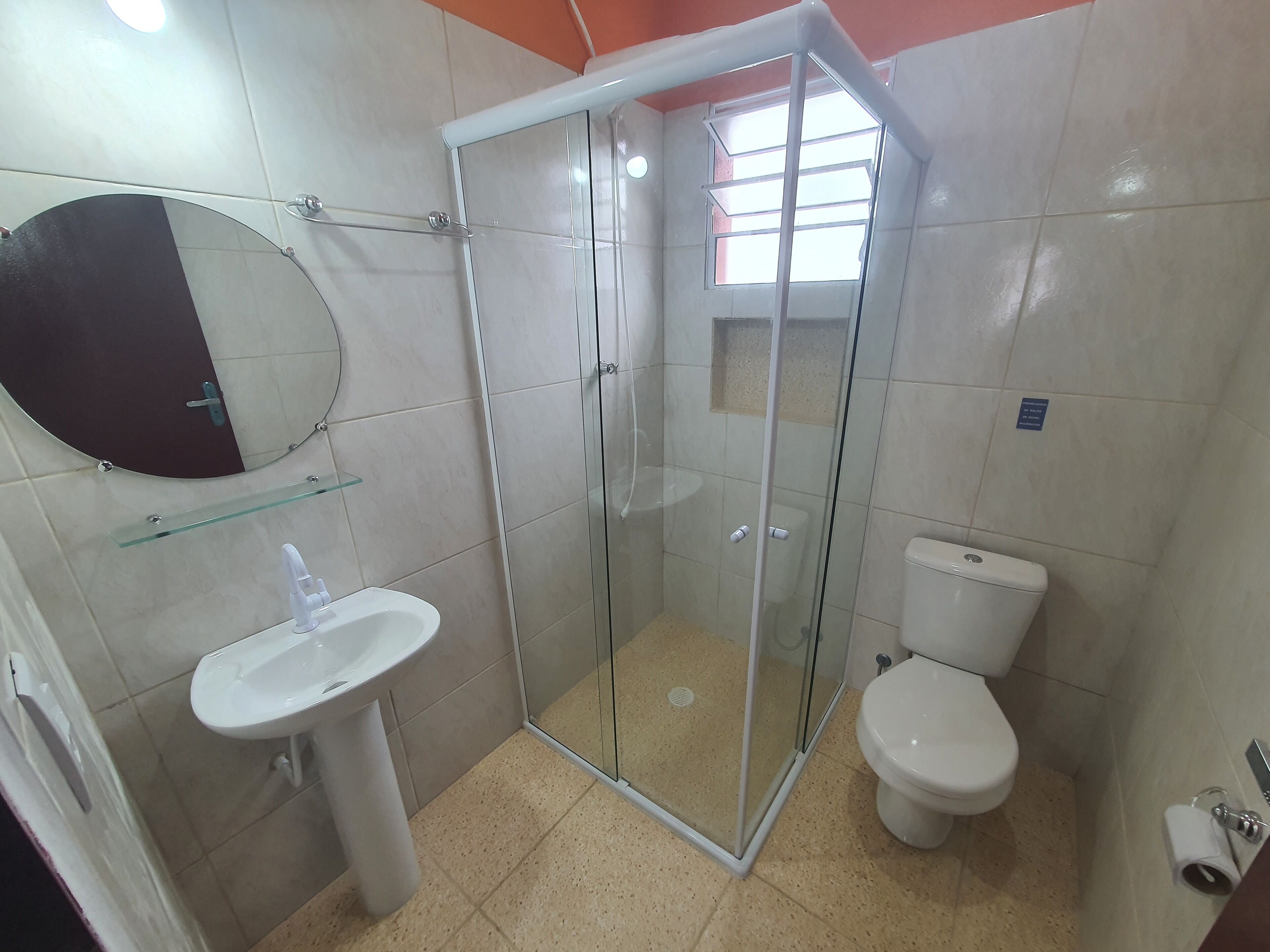 A bathroom with a glass-enclosed shower, a sink, a toilet, and a mirror.