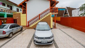 Un estacionamiento con un automóvil Volkswagen y una escalera que lleva a un edificio de techo rojo y barandillas naranjas.