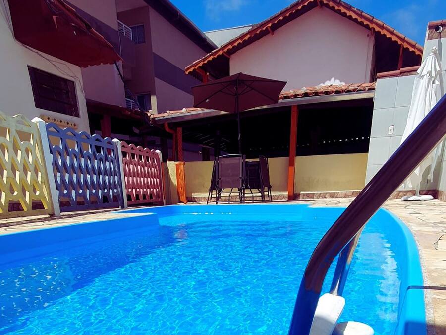 Ein Swimmingpool mit blauer Wasseroberfläche, umgeben von einem Zaun und einem Gebäude mit einem Ziegeldach.