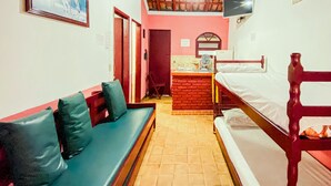 Una habitación con cama, una banca, un televisor y una mesita.