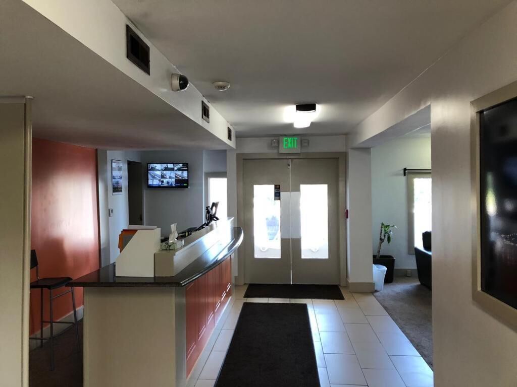 A hotel lobby with a reception desk, a television, and an exit door.