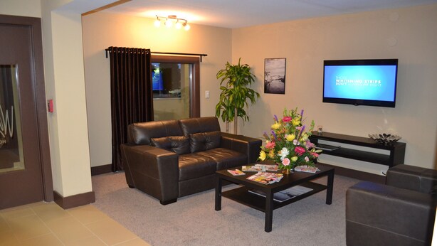 A modern living room with a leather sofa, a coffee table with magazines, a TV, and a potted plant. - Motel 75 Monroe (Monroe)