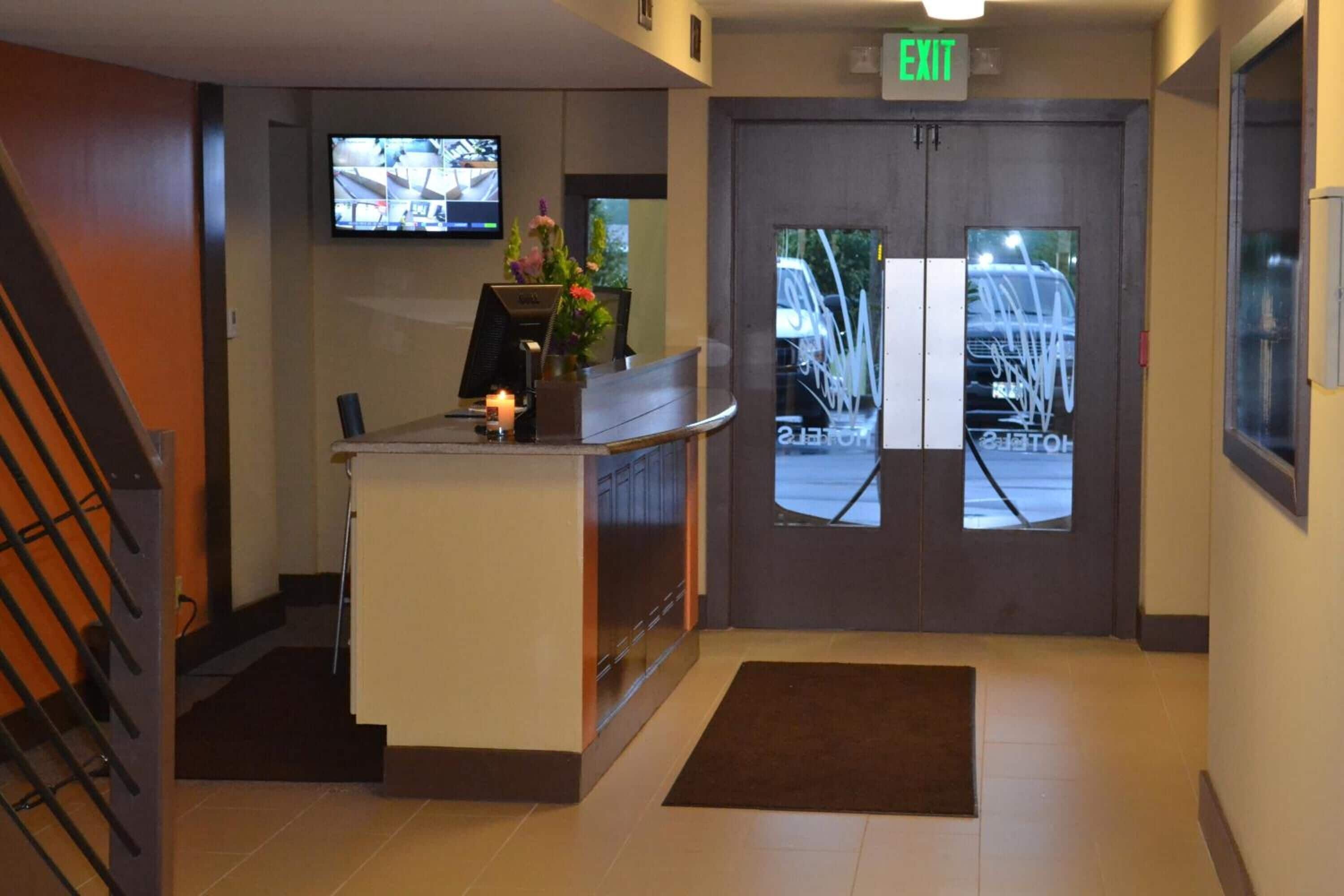 A reception desk with a computer, a small plant, and a sign above the door indicating an exit.