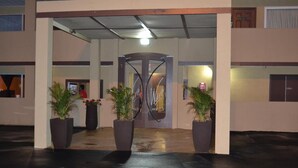 A hotel entrance with a glass door, potted plants, and a sign reading "We Hotels." - Motel 75 Monroe (Monroe)