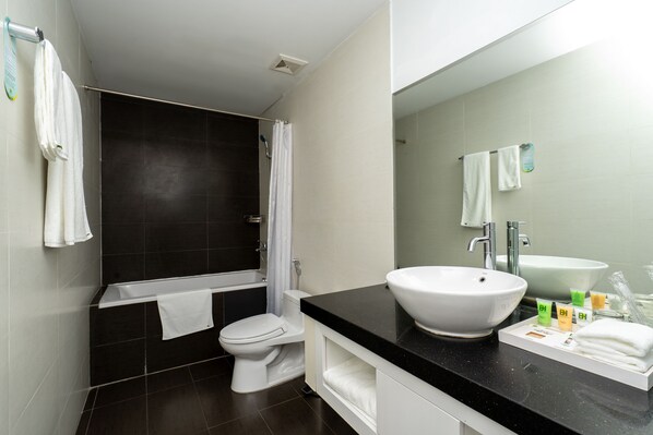 A modern bathroom with a bathtub, toilet, and sink. - Becamex Hotel Thu Dau Mot (Ho Chi Minh City)