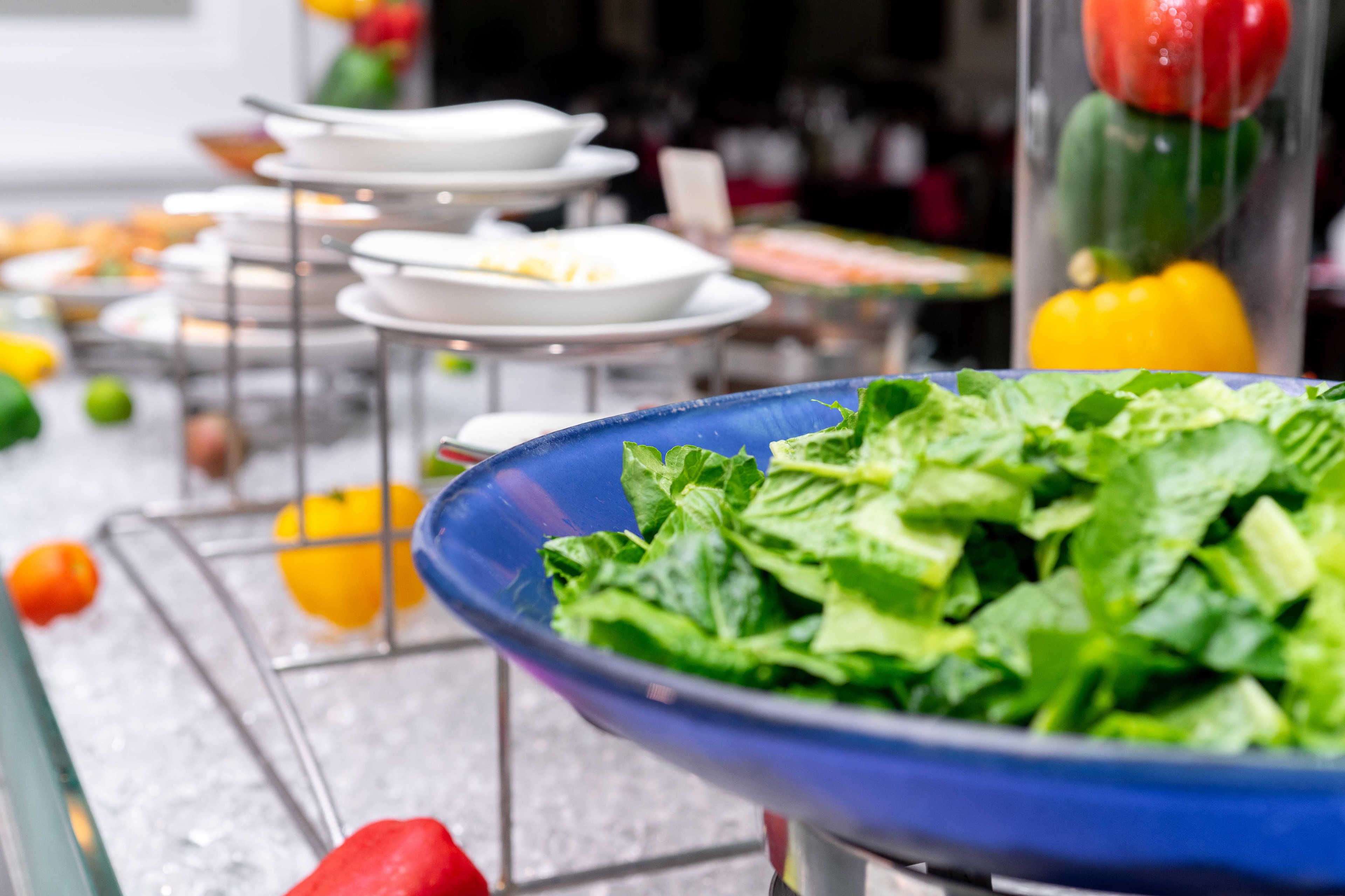 A buffet table with various dishes and fresh vegetables.