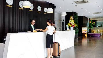 A reception desk with clocks labeled with city names, a large potted plant, and a check-in counter.