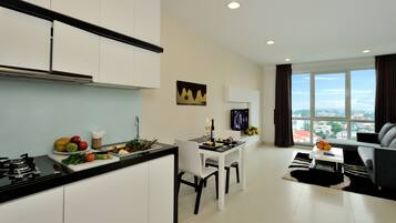 A modern apartment with a kitchen, dining area, and living room. It features a large window with a city view, a flat-screen TV, and a dining table with chairs.